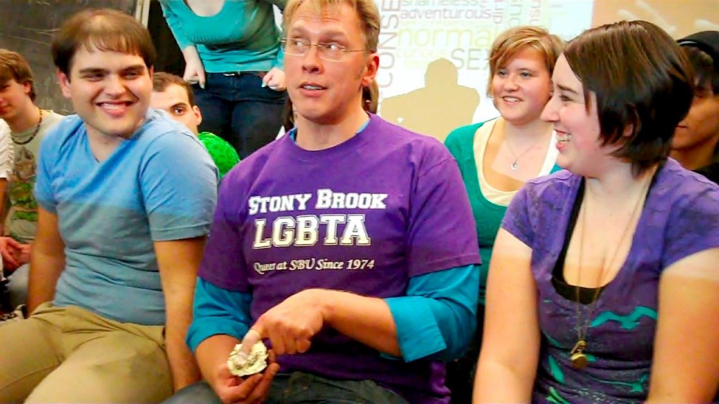 Stony Brook College Feb 2011 Sex and relationship expert Reid Mihalko surrounded by laughing, college-age adults while demonstrating safer sex techniques with a finger cot and a cupcake at Stony Brook College in Long Island