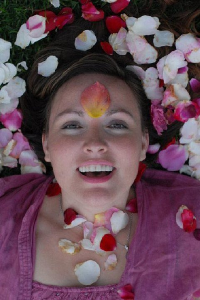 Relationship educator Monique Darling of DivineInterludes.com looking directly into the camera, covered and surrounded with rose petals