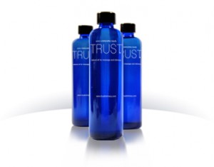 A product shot of three, 10 ounce TRUST Intimacy massage oil bottles