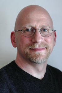 Close up photo of sex educator Charlie Glickman wearing a black tshirt and glasses