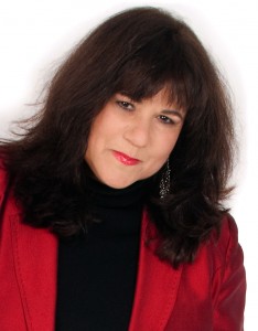 Author of the book, Shameless, Pamela Madsen, wearing a red jacket and black turtleneck