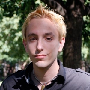 red headed Alex Leavitt in a grey polo shirt standing outdoors