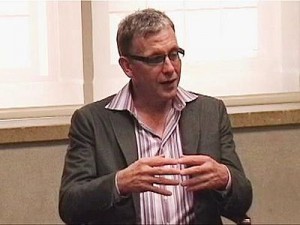 Dr. Marvin Belzer in a stripped shirt and gray suit coat lecturing
