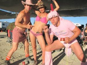 Sex and relationship expert Reid Mihalko at Burning Man wearing bright pink costume sporting a pink dildo on his head and a t-shirt that says, "My Little Pornicorn."