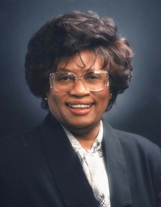 Former US Attorney General, Dr. Jocelyn Elders in a dark blue blazer and white blouse, wearing glasses and smiling