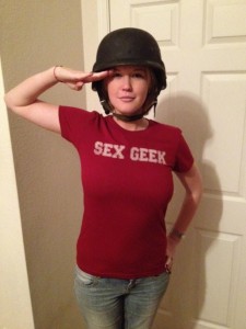 YouTube sex education blogger Kicesie Drew standing at attention, saluting the camera while wearing a ReidAboutSex.com Sex Geek Tshirt and an army helmet