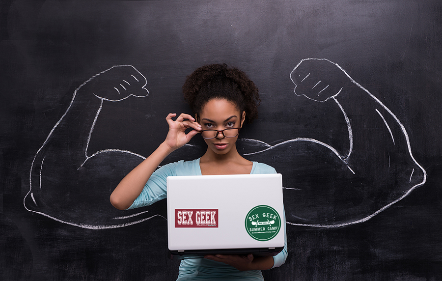 Funny picture of young afro-american woman with laptop with Sex Geek stickers on it standing infront of a chalkboard background. Two strong muscular arms painted on chalkboard.