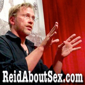 Sex and relationship expert Reid Mihalko wearing a black tux shirt sitting  against red velvet curtains with ReidAboutSex.com in text across the bottom