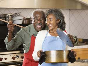 Older, black couple cooking in the kitchen have a blast!