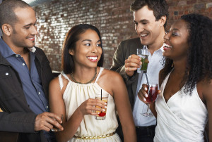 Two happy multiethnic couples with drinks at the bar