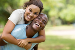 attractive young black couple piggybacking outdoors