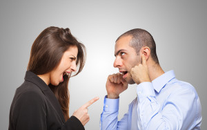 Man covering his ears in front of an angry woman