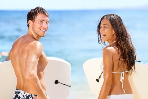 Surfers on beach having fun in summer. Surfer woman and man with