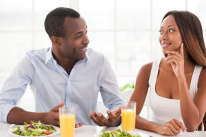 Beautiful young African couple sitting together at the breakfast table and talking