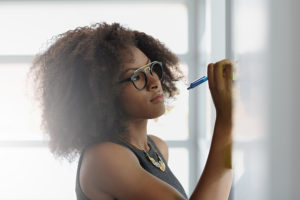 Friendly african american executive business woman brainstorming using green adhesive notes in a modern white office