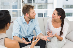 Unhappy couple arguing at therapy session in therapists office