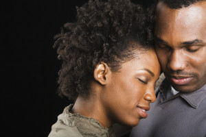 African American couple hugging with eyes closed