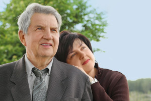 Portrait Of Old Senior In Suit, His Adult Daughter Leans On His