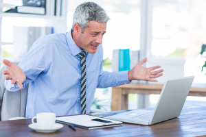 Confused businessman looking at laptop computer in office