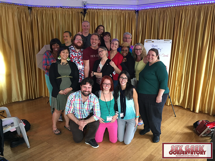Group shot of smiling sex educators and Reid Mihalko in a room with gold curtains during Reid's Sex Geek Conservatory 3-day event