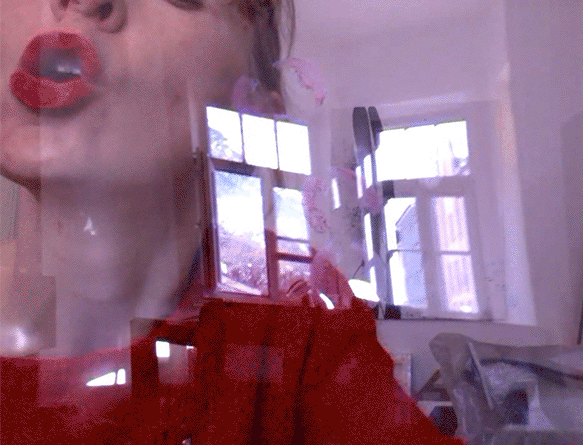 GIF of a white woman wearing a read sweater and red lipstick kissing the window from inside her home