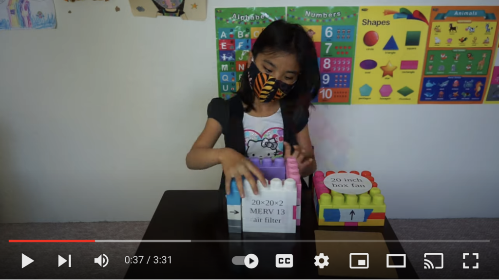 Screenshot from Youtube video of a Asian 4th grader wearing a covid mask and assembling building blocks