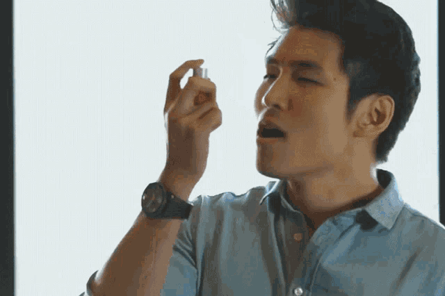 GIF of an asian man using an asthma inhaler and then, in slow motion, him opening wide his arms, as wind blows his dress shirt open in a sign of free airways