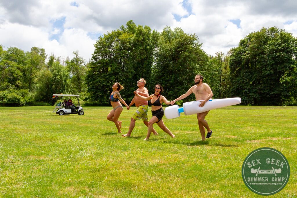 Image of four happy people wearing bathing suits skipping across a green field in summer time