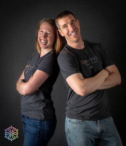 Emma and Fin Standing back to back in black t-shirts and jeans while smiling at the camera, arms folded