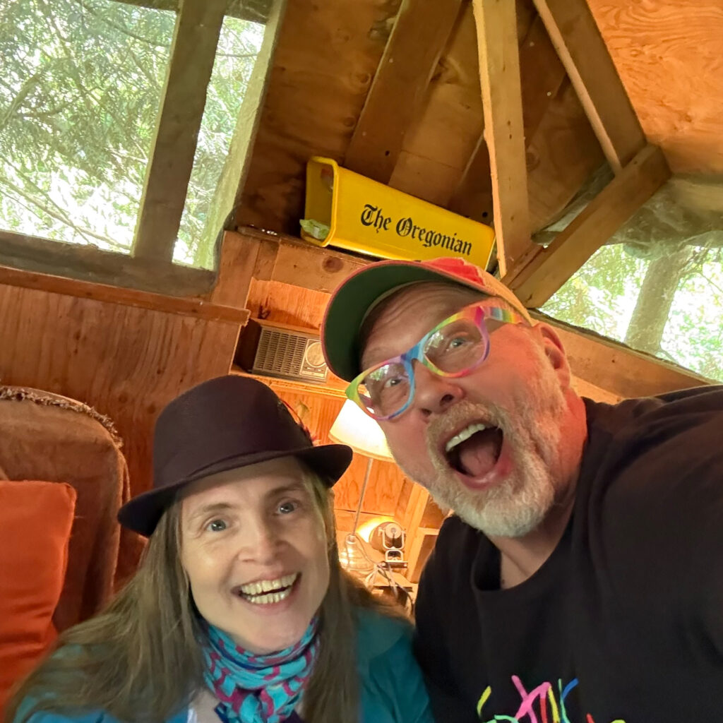 Reid and Monika of Sexplorations with Monika smiling at the camera from inside a tree house.